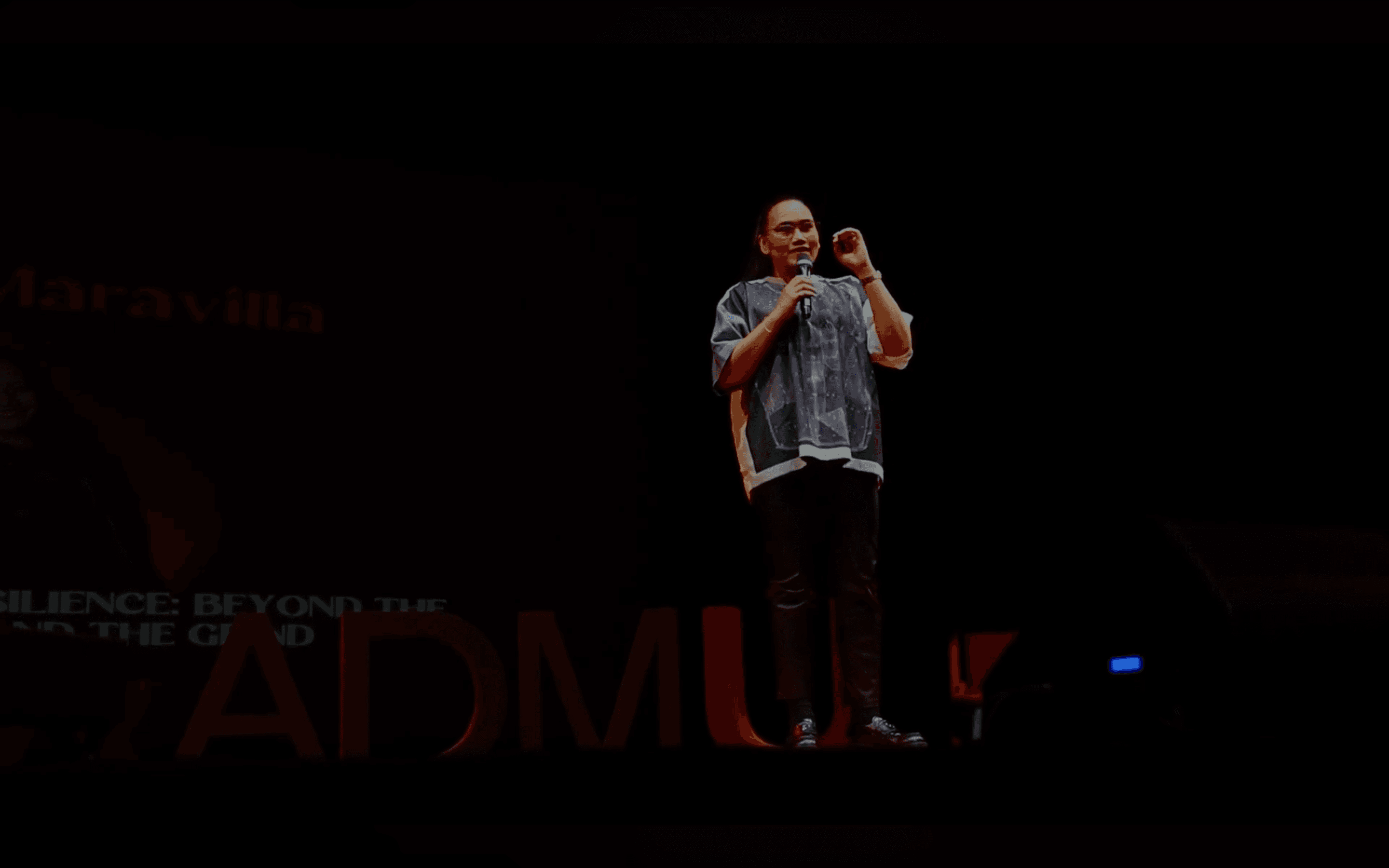 Lyqa Maravilla speaking under a spotlight during her talk.