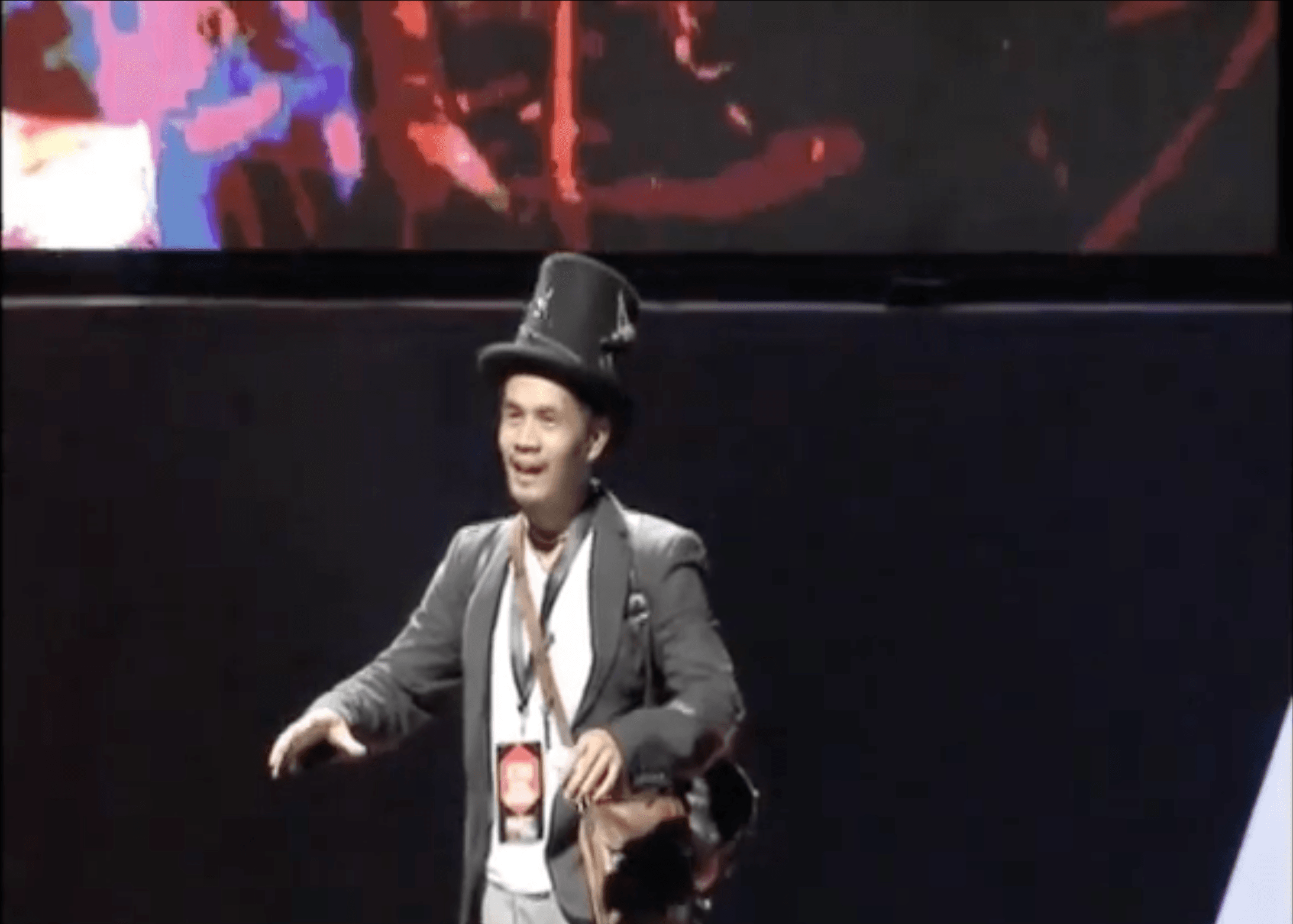 Jetro Rafael performing on stage in a black hat and blazer.